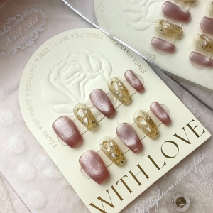 Detail of handmade press-on nails with pink cat eye effect and gold glitter accents
