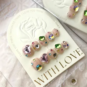Handmade press-on nails in nude pink featuring luxury heart and rectangle gemstones