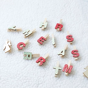 Pinces de Noël en bois avec motifs anges sur un fond blanc de texture douce