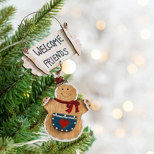Wooden gingerbread man Christmas ornament with Welcome Friends sign hanging on tree