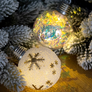 Christmas LED ornament balls with snow patterns and sequins on snowy pine branches
