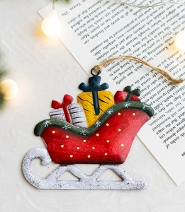 Detail of red iron Christmas sleigh ornament with snow coating and gift boxes