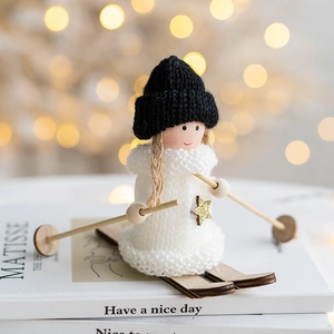 Poupée ange de Noël en peluche faite main avec skis en bois sur décor de livre blanc