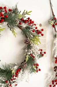 Close-up of Christmas wreath featuring red berries, frosted pine needles and pine cones