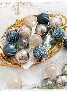 Close-up of assorted gold and red Christmas ornaments with glitter patterns on snow
