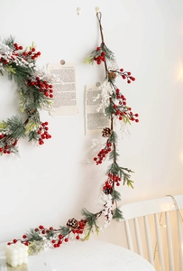 Detail of Christmas garland with pine needles, red berries, and snow-dusted pine cones