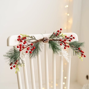 Christmas wreath swag with red berries, pine needles and pine cones on a white chair