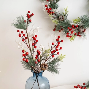 Christmas wreath branch with red berries, pine needles and cones in a blue vase