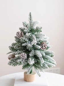 Mini tabletop flocked Christmas tree with pine cones and a natural wooden base