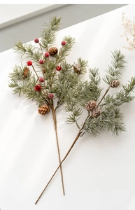 Detail of artificial Christmas pine branch with natural pine cones, red berries and bells