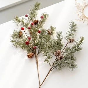 Artificial Christmas pine branches with red berries and pinecones on a white background