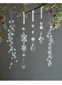 Detailed view of clear acrylic snowflake and teardrop ornaments hanging on Christmas tree