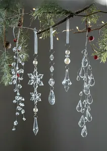 Detail of transparent acrylic snowflake and waterdrop ornaments hanging on a Christmas tree
