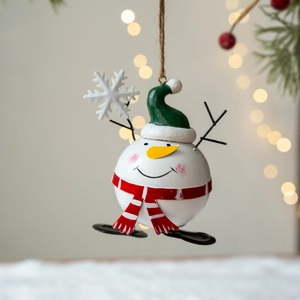 Christmas snowman metal ornament with green hat and red scarf hanging on festive background