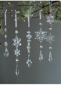 Detailed macro view of clear acrylic snowflake and icicle ornaments on a festive pine branch