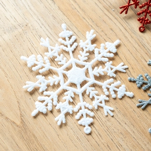Glittery white plastic snowflake ornament for Christmas tree decoration on wooden surface
