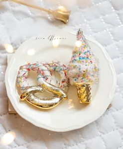 Close-up of sparkling Christmas tree ornaments with pretzel and ice cream cone shapes
