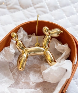 Macro detail of glossy golden balloon dog ornament on white tissue in a wooden box