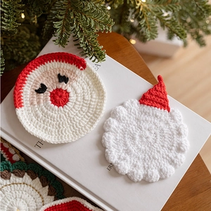 Handcrafted knitted Christmas coasters featuring Santa Claus design for holiday table decor