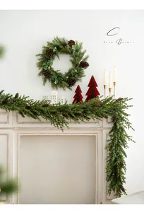 Detail of forest style Christmas PE wreath and garland with pinecones on white fireplace
