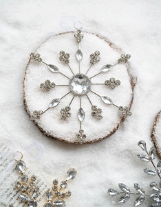 Macro shot of silver acrylic snowflake ornament with inlaid rhinestones on wood slice