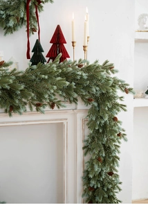 Realistic frosted green Christmas garland with pine cones on a fireplace mantel