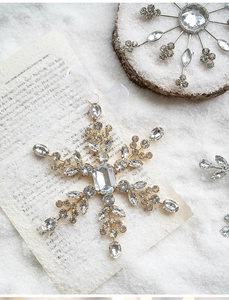 Detailed view of acrylic snowflake ornament with inlaid rhinestones and white ribbon
