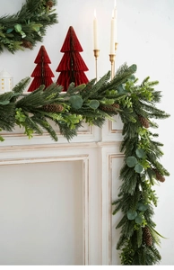 Christmas pine needle garland with pine cones and eucalyptus on a white vintage fireplace