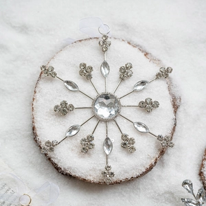 Sparkling silver snowflake ornament with rhinestones on rustic wood and snow background