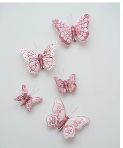 Dettaglio macro di 5 fermagli per capelli a farfalla glitterati rosa con perle e clip