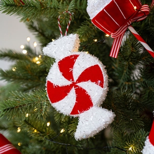 Red and white swirl glitter candy cane hanging ornament on a decorated Christmas tree