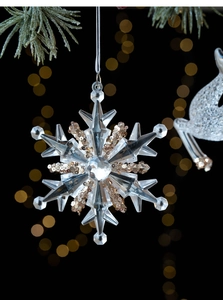 Close-up of a sparkling acrylic snowflake ornament with gold sequins on a Christmas tree