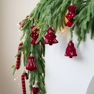 Red velvet Christmas ornaments set hanging on a pine branch with warm festive lights