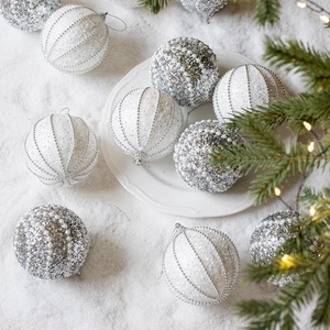 Palline di Natale bianche e champagne sulla neve con rami di pino e luci calde soffuse