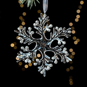 Sparkling silver glitter snowflake ornament made of transparent acrylic on black background
