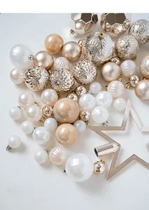 Macro shot of assorted champagne gold and pearl white plastic Christmas ornaments with tree topper