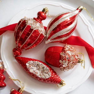 Set of luxury red Christmas tree ornaments with gold glitter details in a white dish