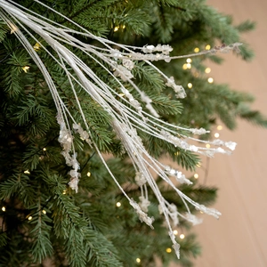 Sparkling white Christmas glitter spray with translucent crystals on tree branch