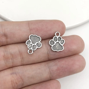 Detail of silver cat paw charms for DIY jewelry making showing texture and size