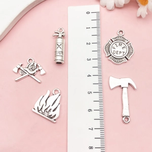 Detail of five antique silver fire extinguisher charms with ruler for size measurement