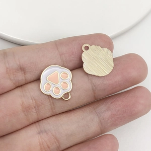 Macro detail of alloy paw print pendant showing golden finish and pink enamel texture