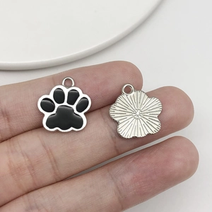 Macro detail of paw print pendant showing black enamel finish and metal texture