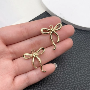 Primer plano de pequeños colgantes de lazo dorado con anillas para creación de joyería
