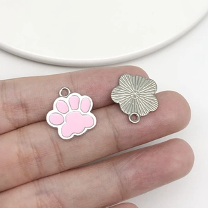Detailed view of pink enamel cat paw charm and silver sunburst pendant with back texture