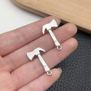 Macro view of two silver axe pendants for DIY jewelry making held in hand for scale