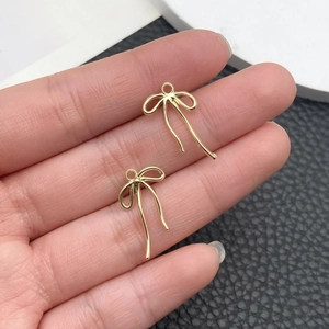 Primer plano de dijes de lazo dorados con bucles para creación de joyas artesanales