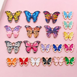 Vue détaillée de breloques papillons colorées en émail avec bordures en métal doré rose