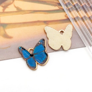 Detailed macro view showing the front enamel pattern and textured gold back of butterfly pendants