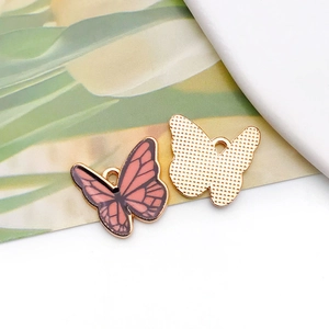 Detailed macro view of pink butterfly alloy pendant with enamel finish and golden back
