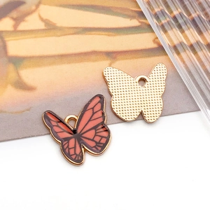 Macro shot of orange enamel butterfly charm with gold alloy frame and textured back